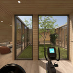 Private mini gym with exercise bike, weight equipment and full-height windows overlooking the landscaped central courtyard of the ultimate 2 person glamping pod.