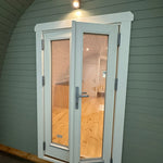 Angled exterior view of The Twilight Pod luxury 2 person glamping pod with curved roof and front entrance door