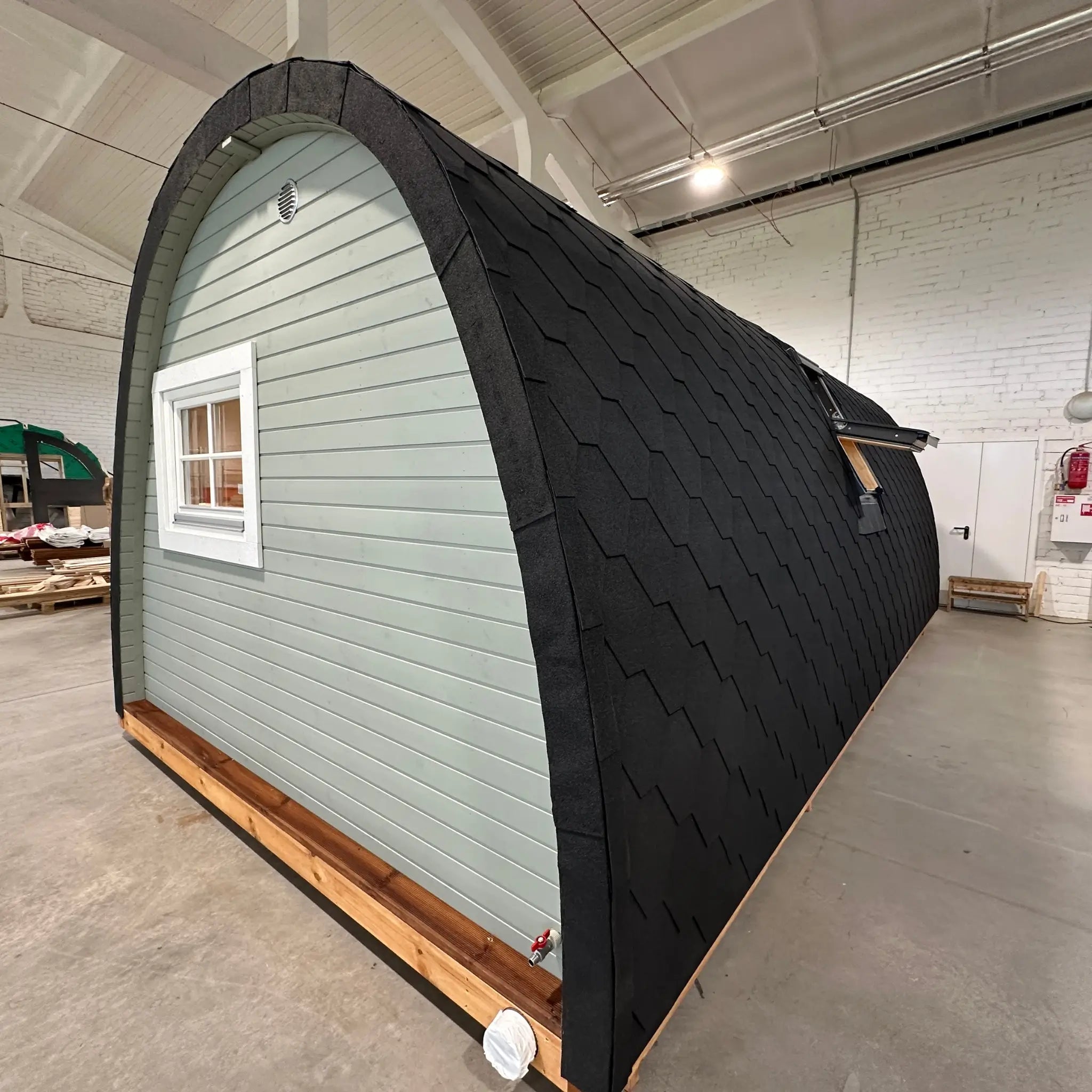 Side exterior view of The Twilight Pod luxury 2 person glamping pod with curved roof and side window