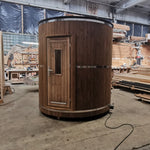 Front exterior view of The Washwood Barrel showing timber cladding, entrance door, and cylindrical form.