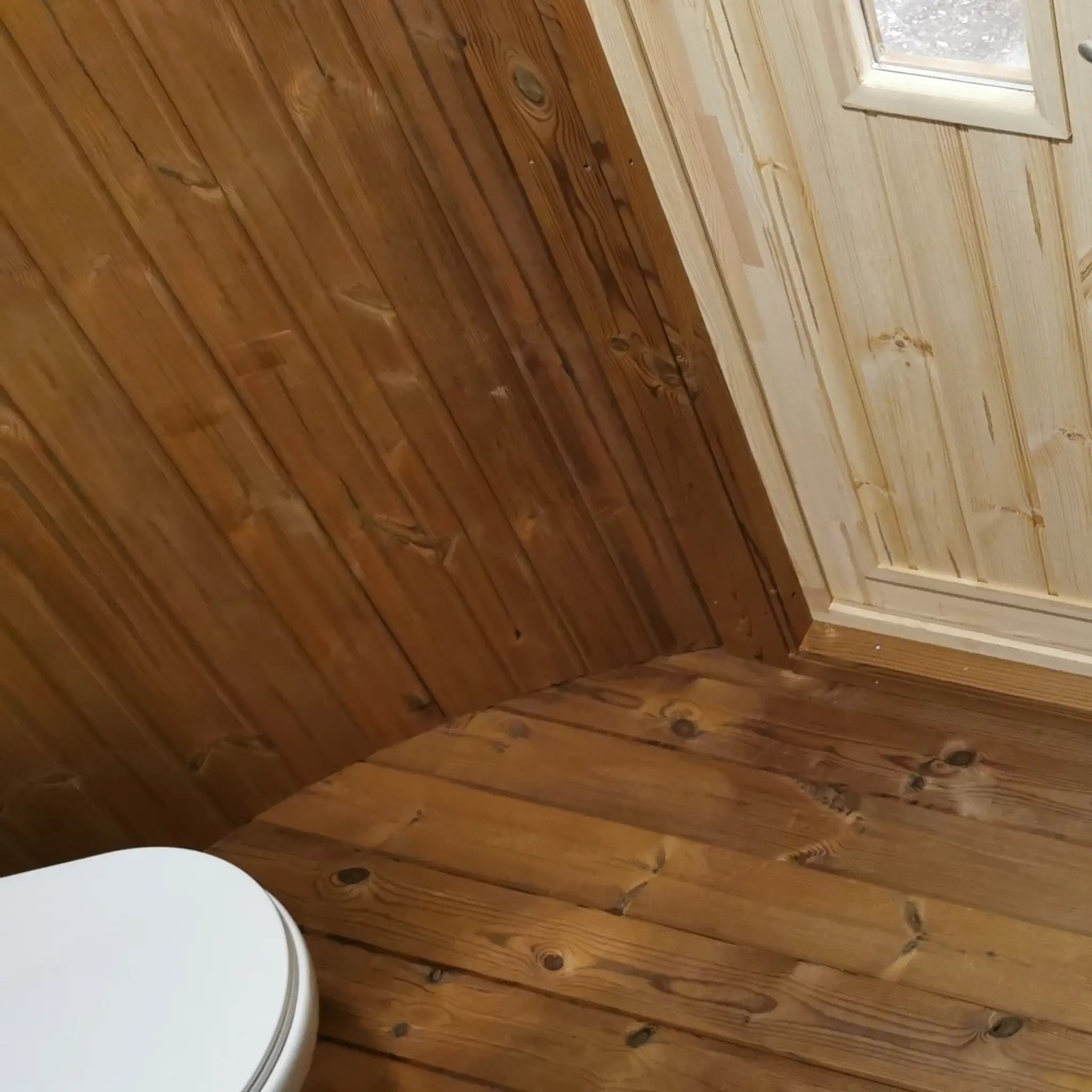 Interior floor detail of The Washwood Barrel featuring timber flooring and curved wall junction.