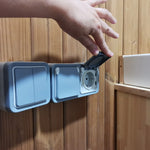 Interior wall-mounted electrical socket inside The Washwood Barrel with protective weatherproof cover open.