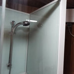 Shower enclosure inside the Washwood Barrel with frosted glass panels and chrome shower head