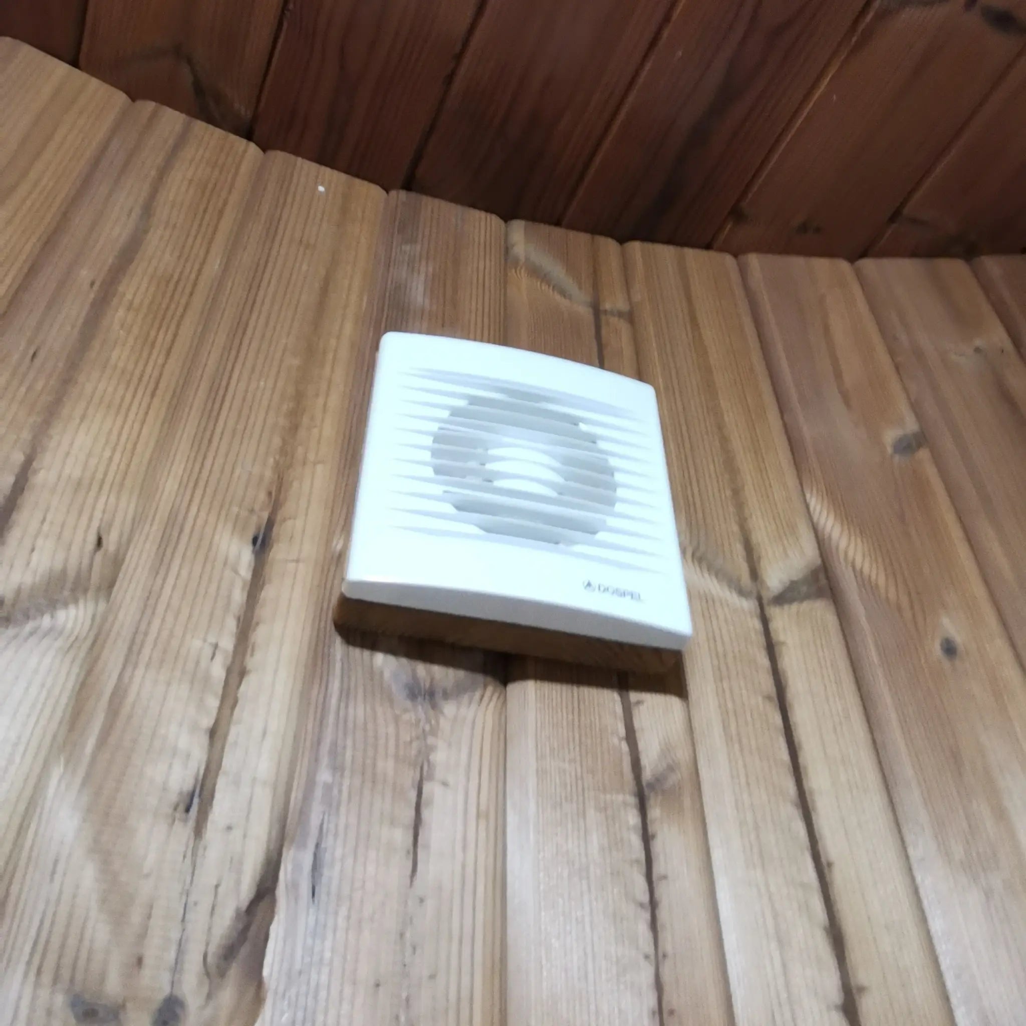 Wall-mounted ventilation fan on timber cladding inside the Washwood Barrel bathroom