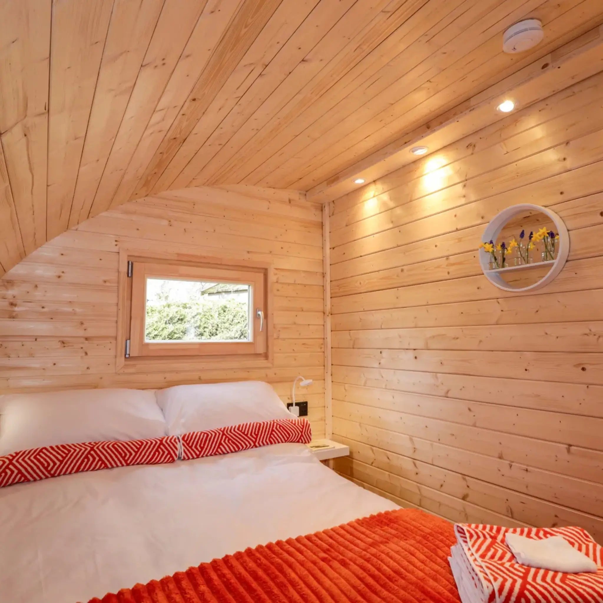 Cosy double bedroom inside The Dual Halfmoon luxury 4 person glamping pod with timber interior and bedside lighting