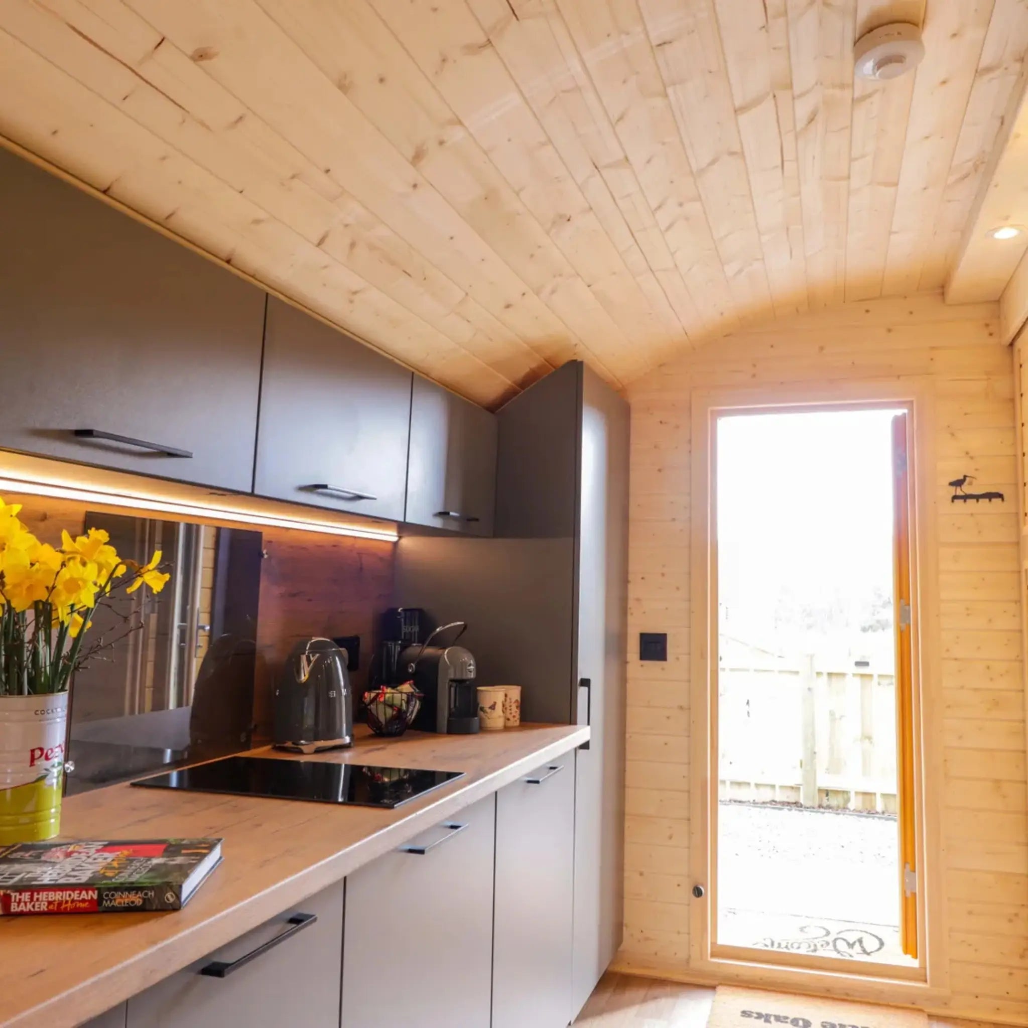 Entrance hallway and modern kitchenette inside The Dual Halfmoon luxury 4 person glamping pod with integrated appliances