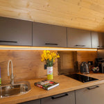 Contemporary kitchenette inside The Dual Halfmoon luxury 4 person glamping pod with fitted cabinets, induction hob and worktop