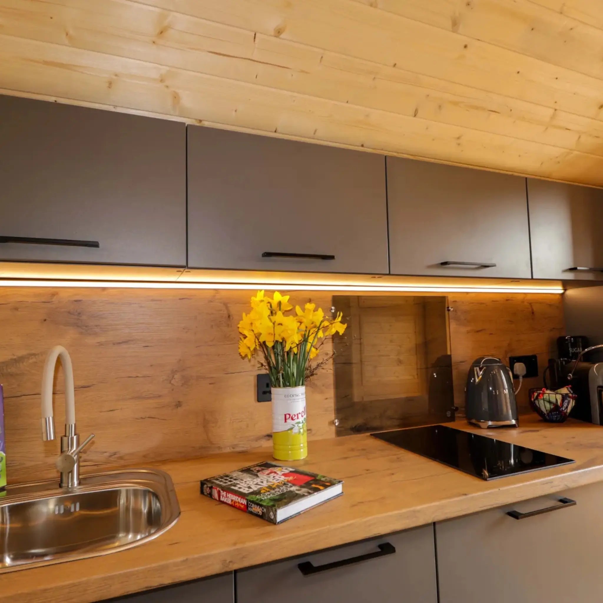 Contemporary kitchenette inside The Dual Halfmoon luxury 4 person glamping pod with fitted cabinets, induction hob and worktop
