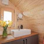 Modern bathroom sink and vanity area inside The Dual Halfmoon luxury 4 person glamping pod with timber interior and feature mirror