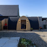 Luxury Hobbit garden office pod exterior front view with double doors, curved timber frame and black shingle roof in modern backyard