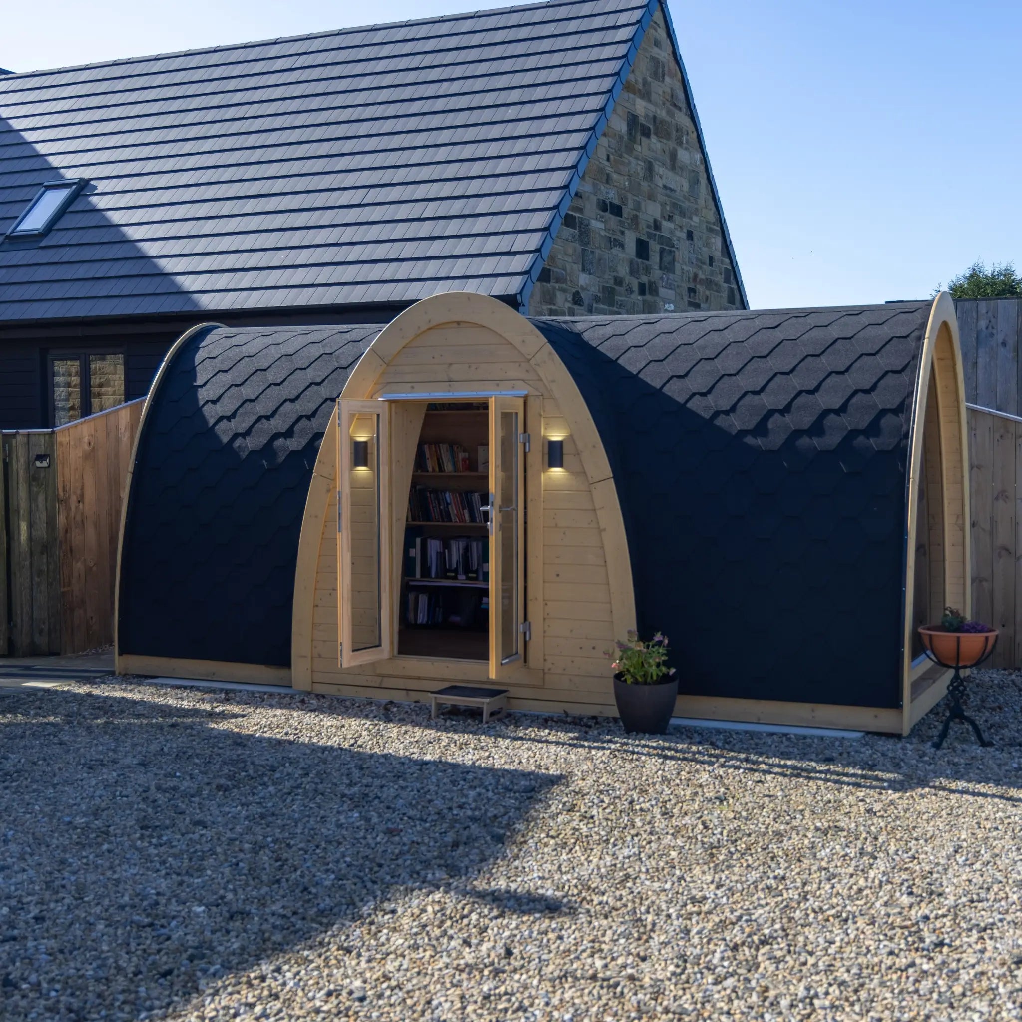 Full exterior side view of Hobbit garden office pod with arched structure, black shingle roof and modern backyard setting