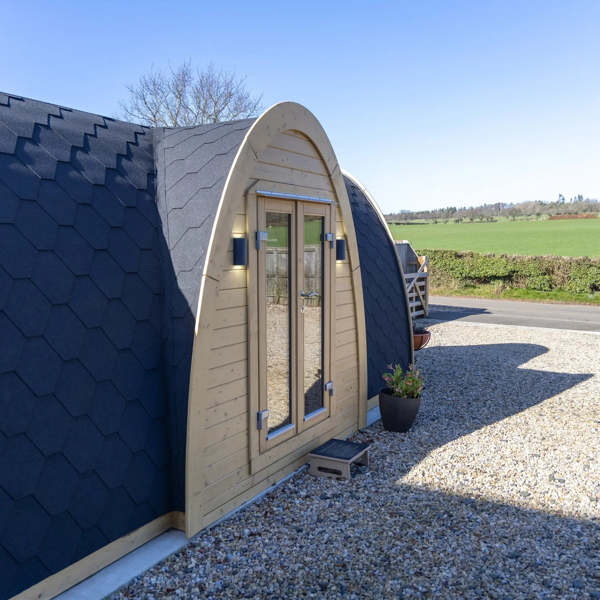 Side view of Hobbit garden pod showcasing compact footprint, curved design and natural wood exterior in residential garden