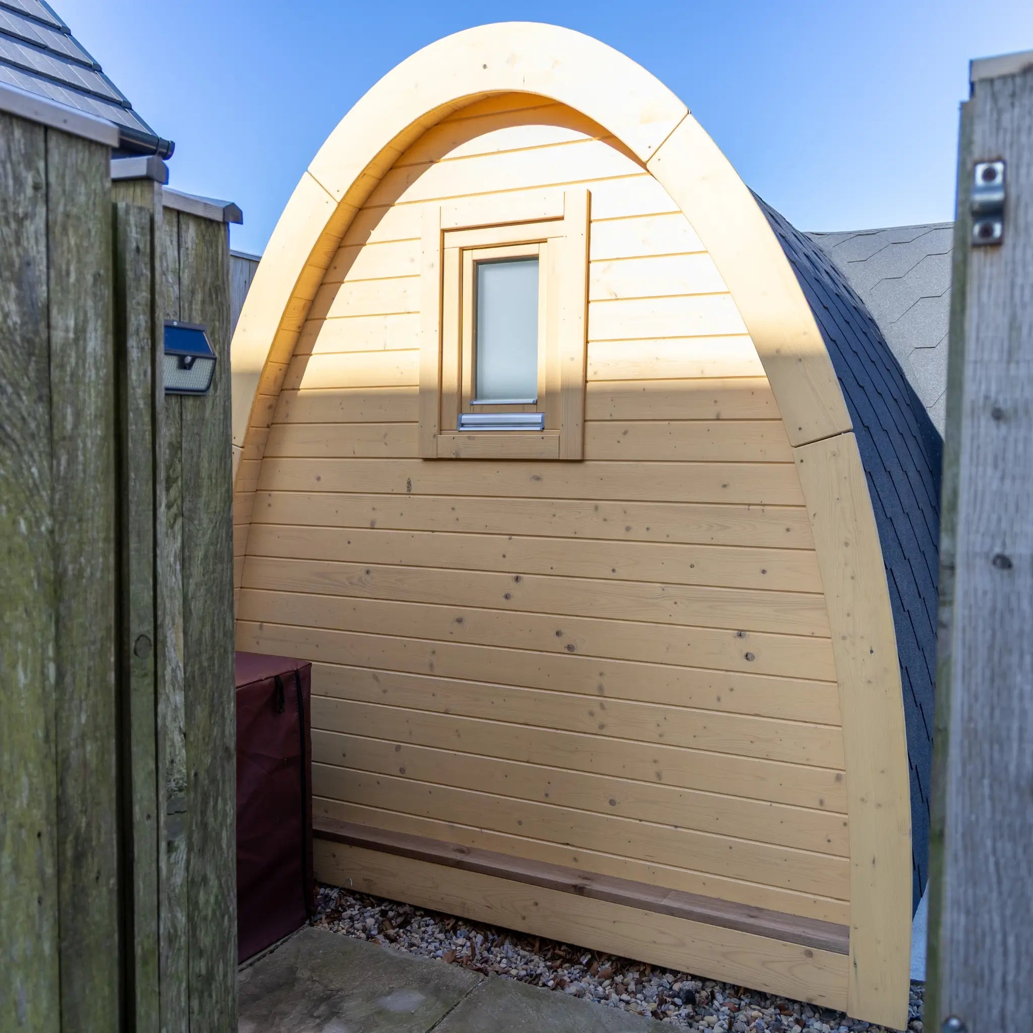 Rear view of Hobbit garden office pod with small window, natural timber cladding and curved roof design in compact outdoor space