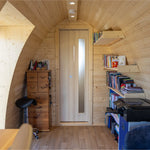 Interior of Hobbit garden office pod styled as personal workspace with shelving, storage and warm timber finish