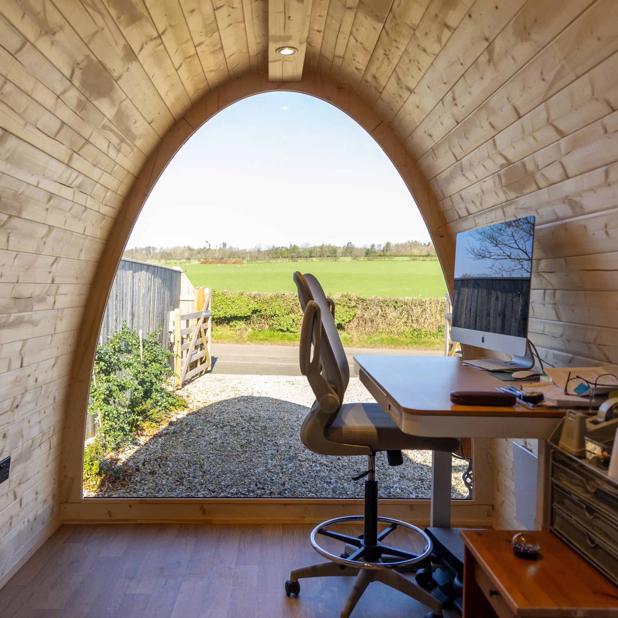 Interior desk setup inside Hobbit garden office pod with ergonomic chair and full glass wall overlooking countryside views