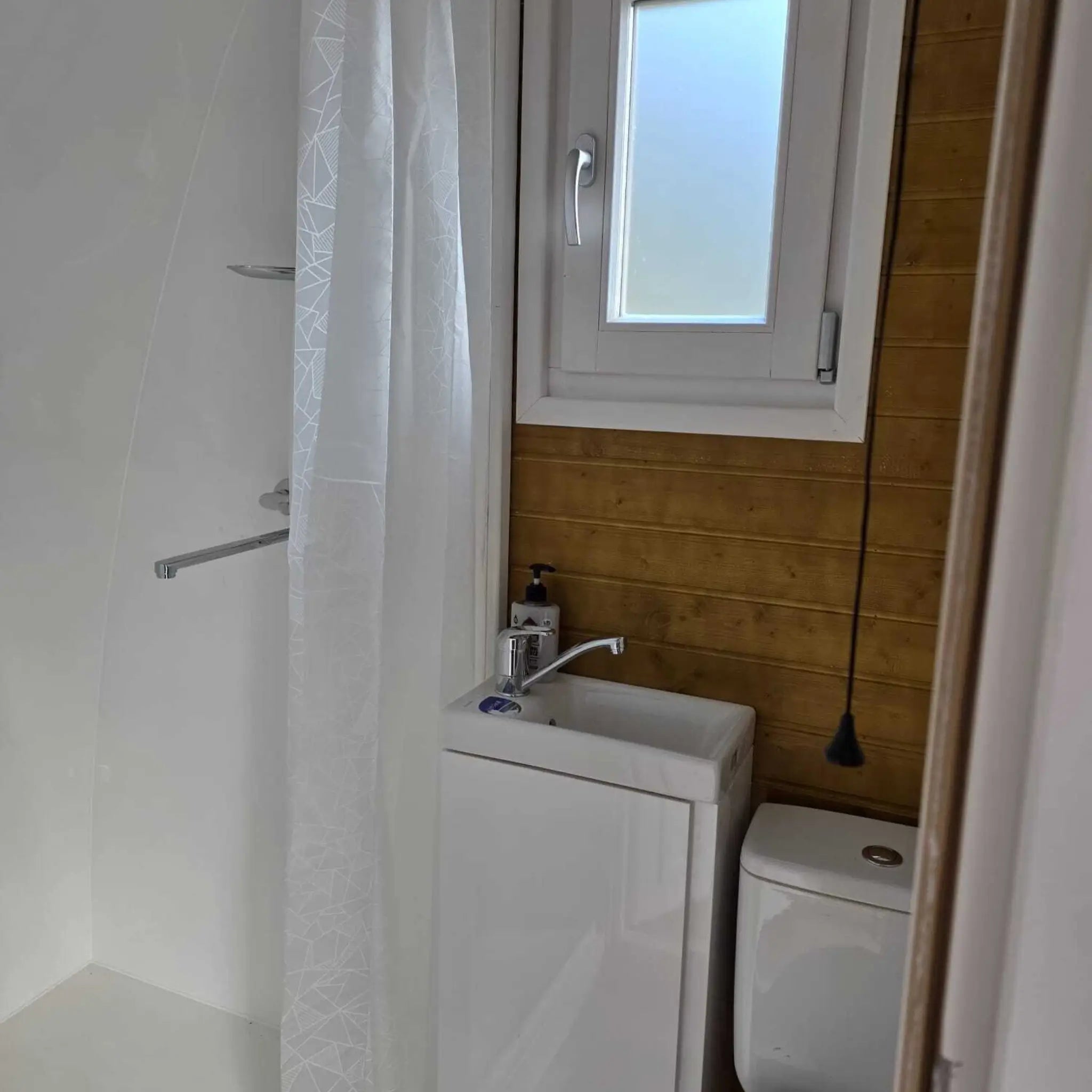 Modern compact bathroom inside Hobbit glamping pod with shower, toilet and sink in space-saving layout