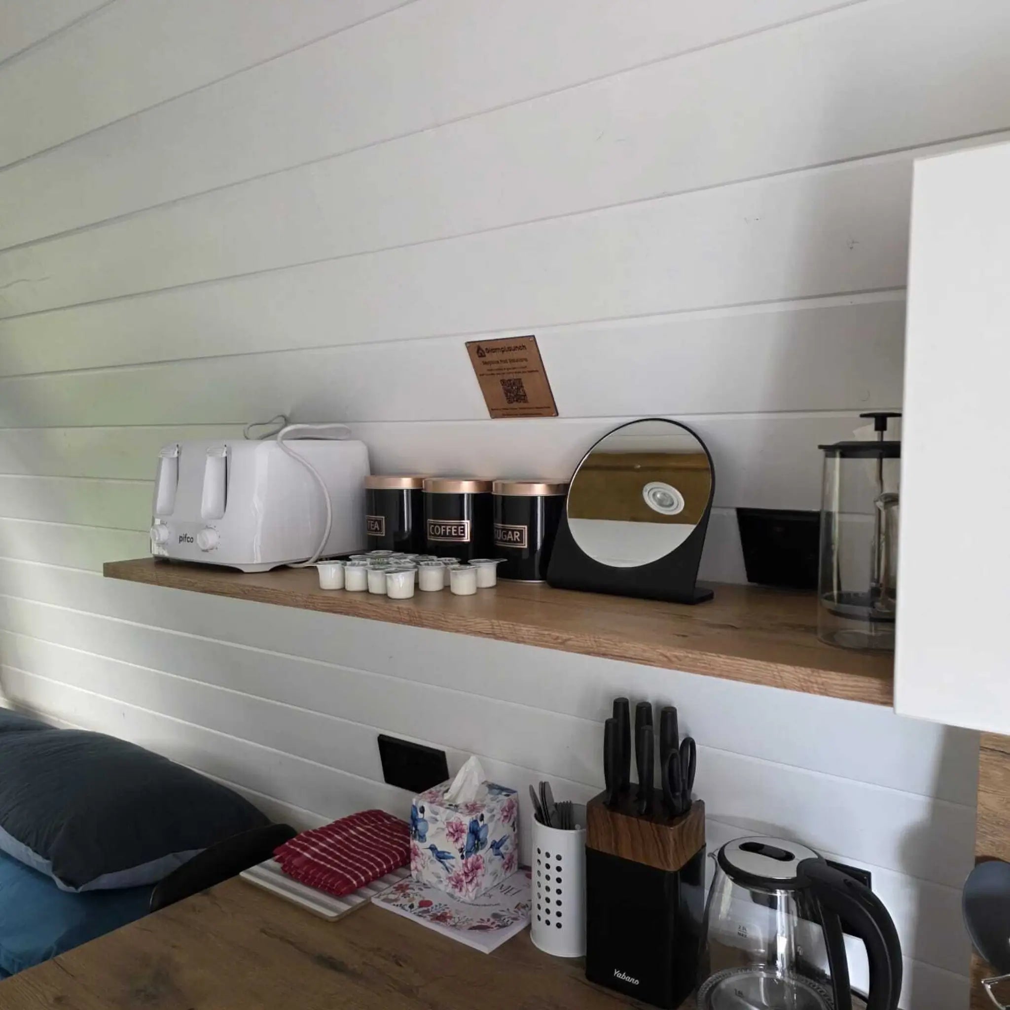 Kitchen shelf with toaster, coffee station and storage jars inside Hobbit glamping pod interior