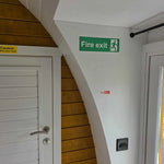 Interior doorway with fire exit sign and curved wall design inside Hobbit luxury glamping pod
