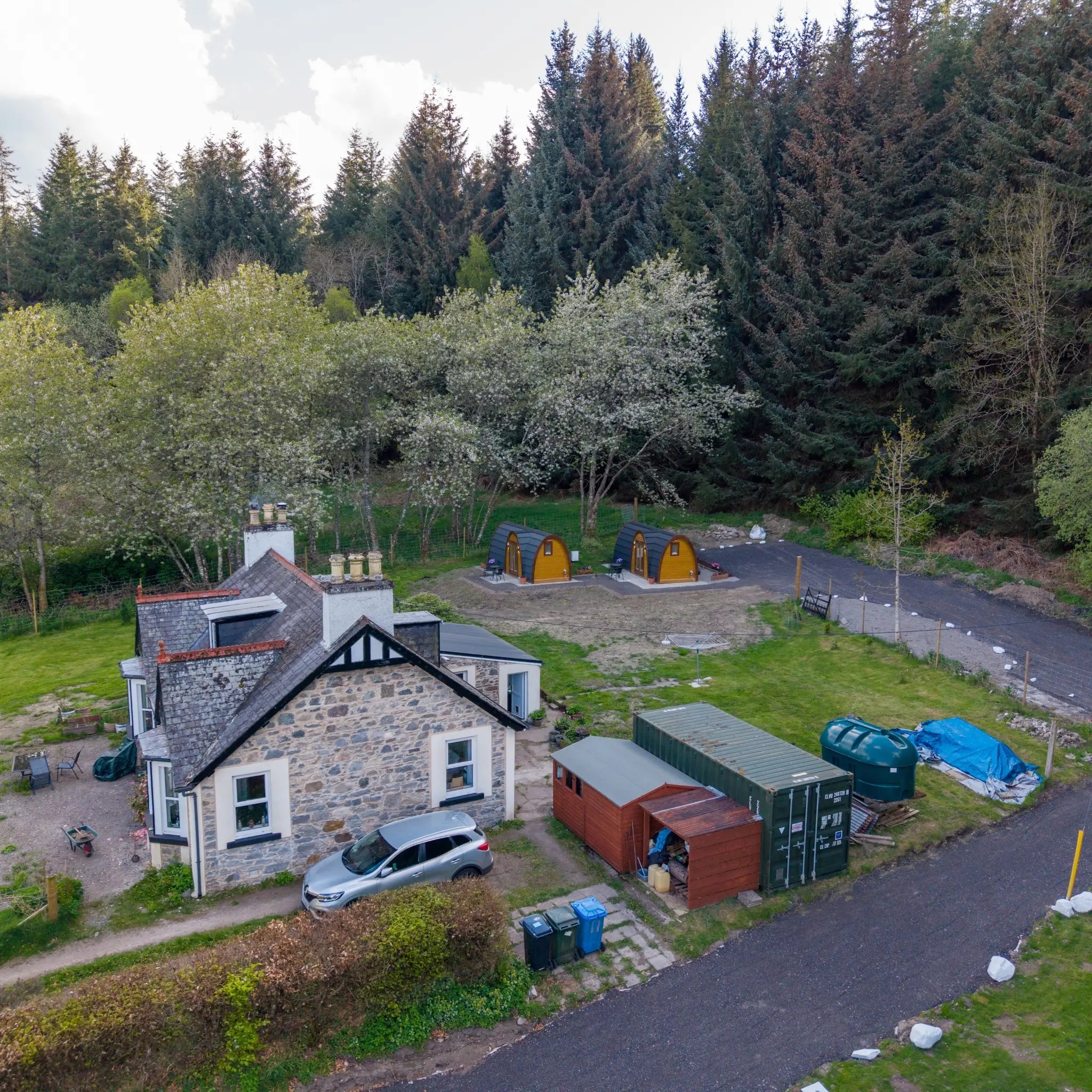 Aerial view of two luxury glamping pods beside a countryside cottage