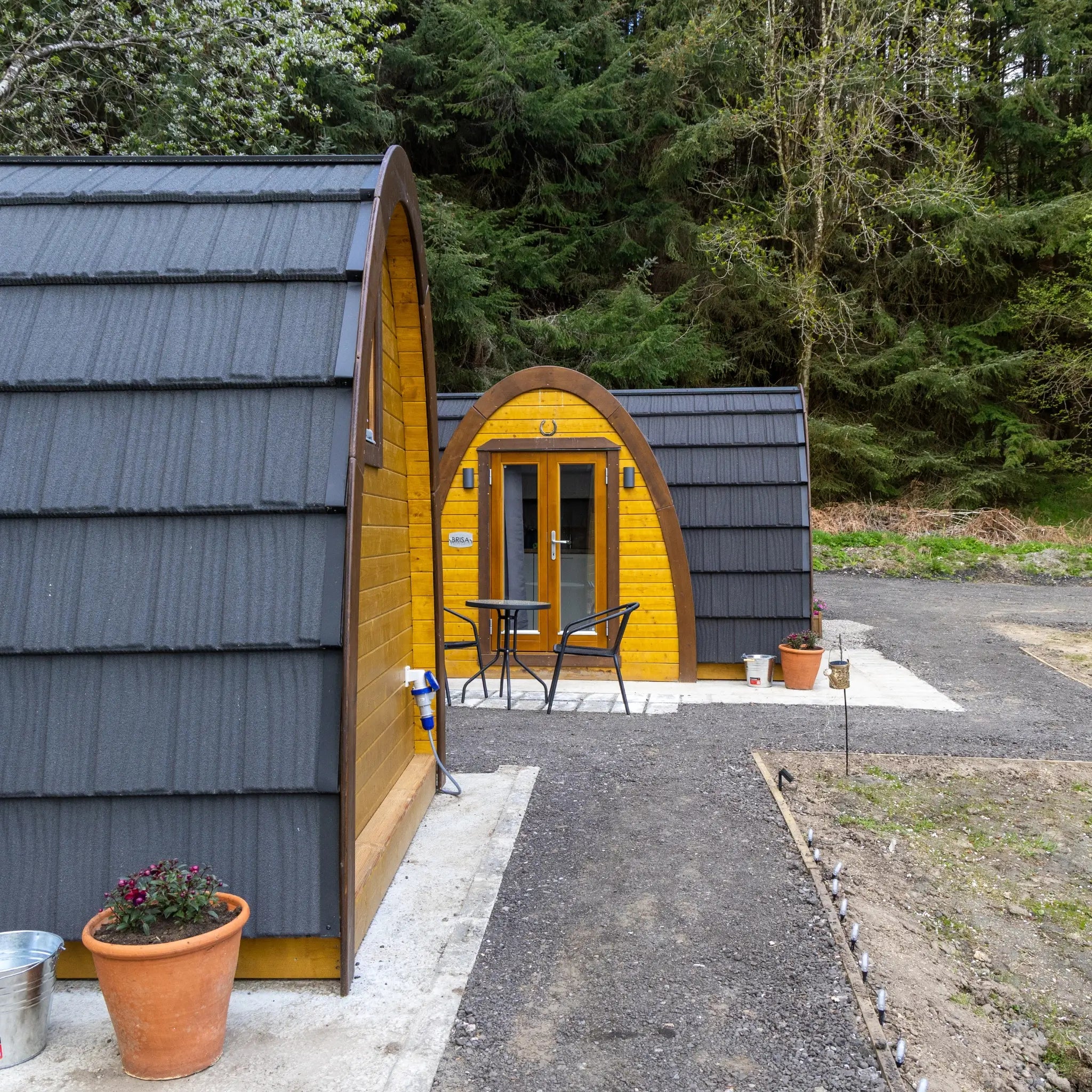 Front view of luxury timber glamping pod with outdoor seating area