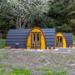 Two luxury glamping pods with private patios in woodland surroundings