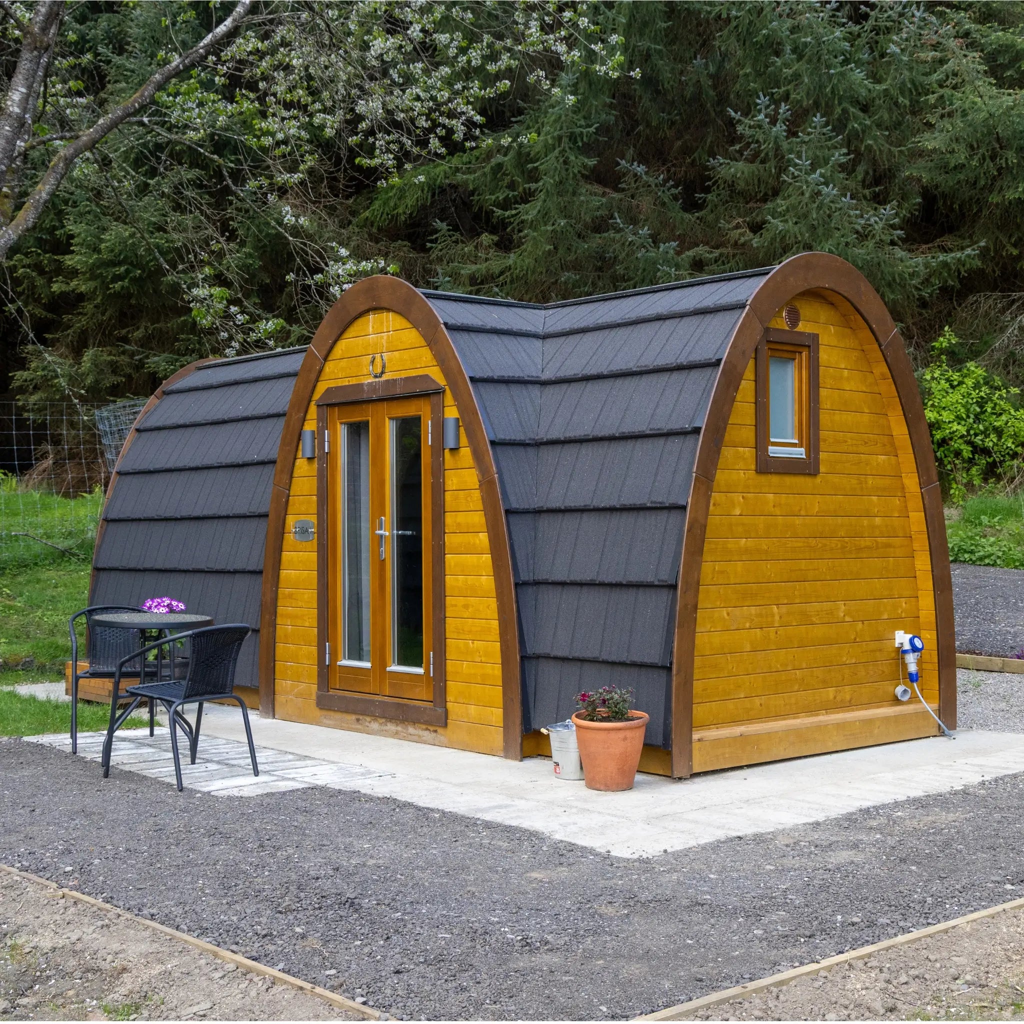 Exterior side view of the luxury 2 person Hobbit glamping pod with timber cladding and arched roof design