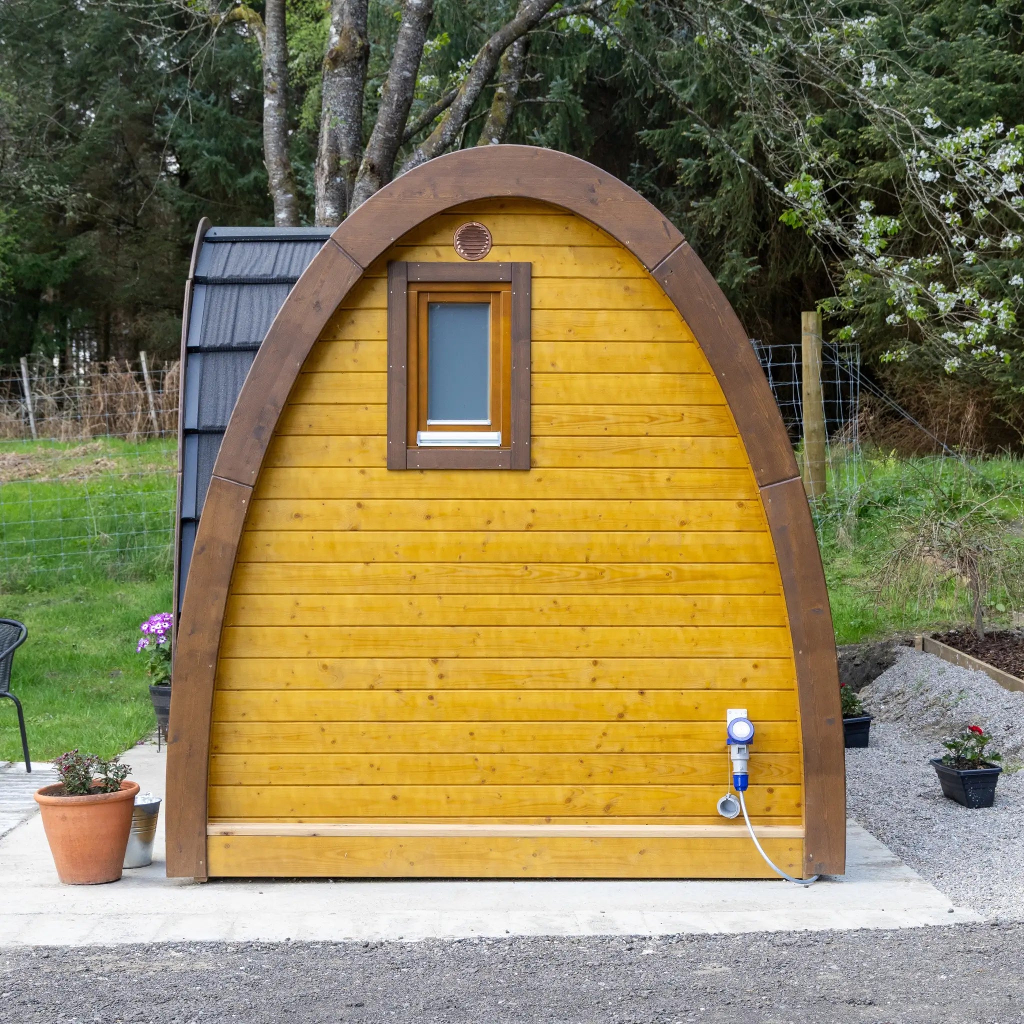 Side view of luxury glamping pod with curved roof and panoramic rear window