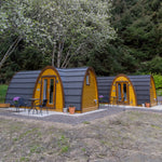 Side view of two luxury glamping pods with woodland backdrop