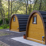 Side elevation of two glamping pods with side windows and curved design
