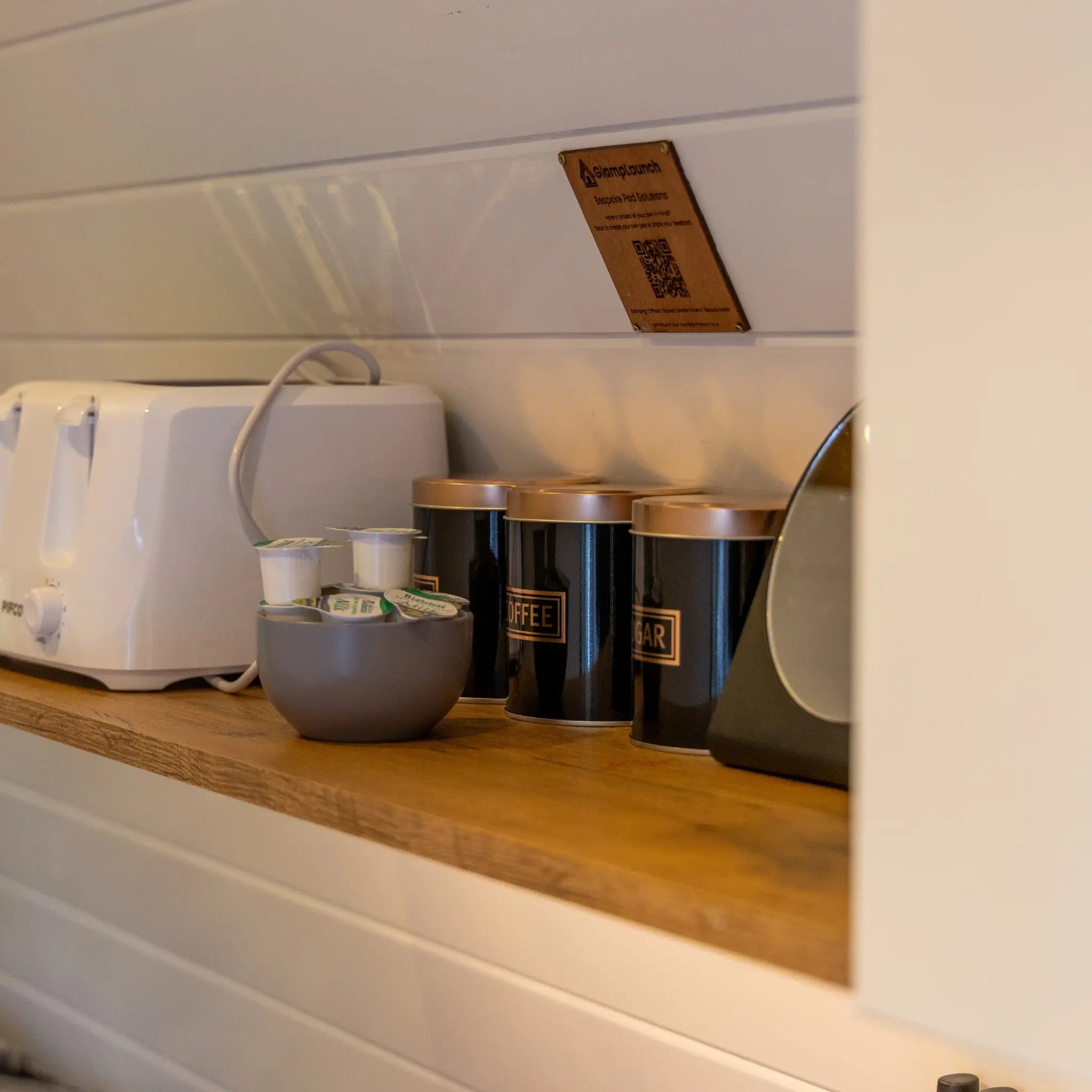 Compact kitchenette shelf with toaster, tea and coffee facilities inside a luxury Hobbit glamping pod