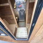 Luxury 8 person barrel sauna changing room with bench seating viewed through the open entrance door