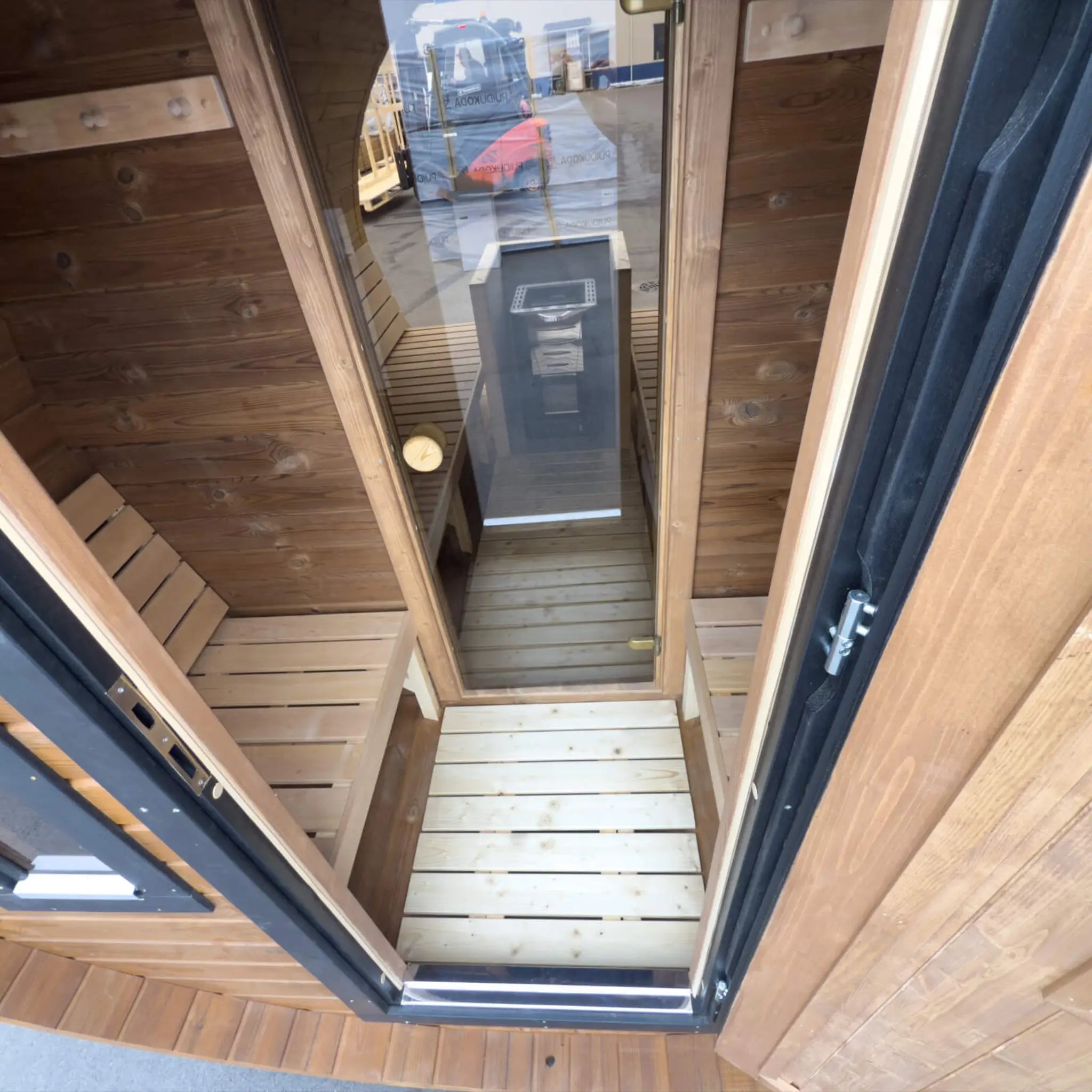 Luxury 8 person barrel sauna changing room with bench seating viewed through the open entrance door