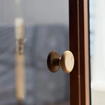 Glass sauna door with solid timber handle leading to the changing room in a luxury barrel sauna