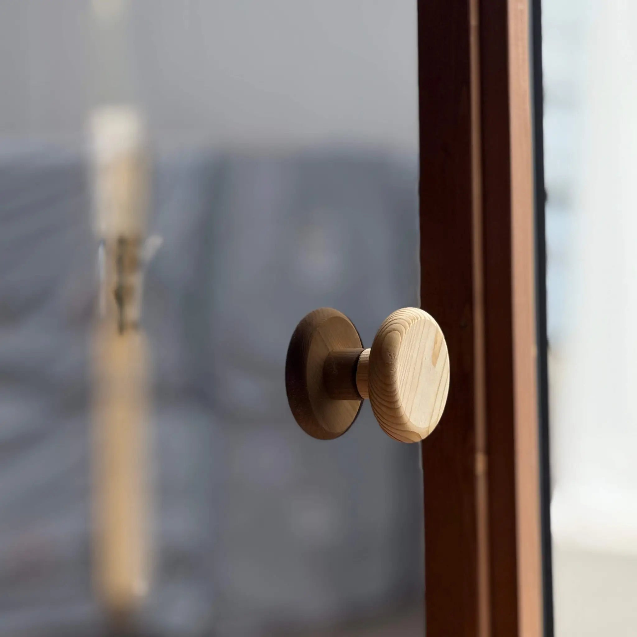 Glass sauna door with solid timber handle leading to the changing room in a luxury barrel sauna