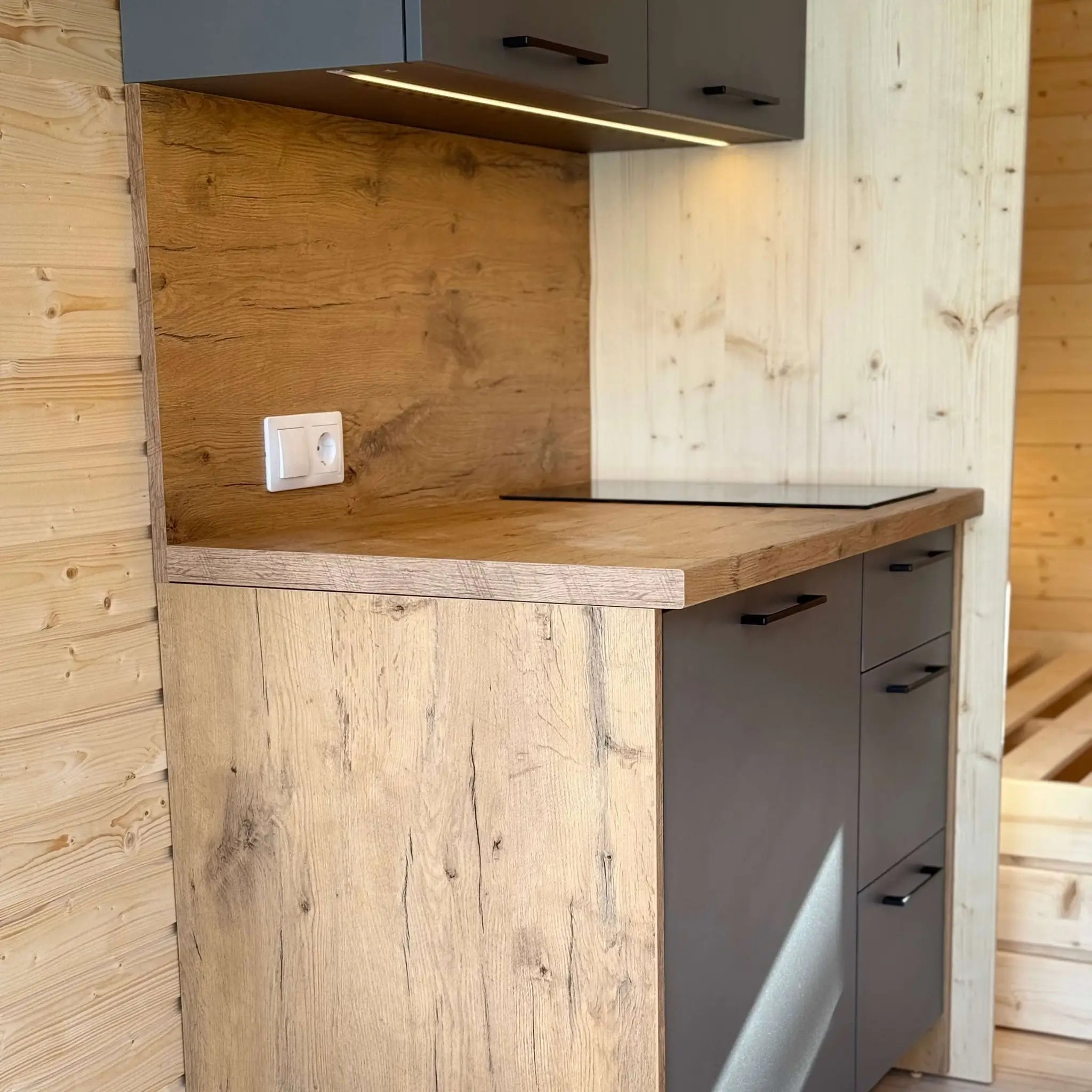 Compact kitchenette in The Ridgefall Pod 2 person glamping pod with timber worktop and modern cabinetry.