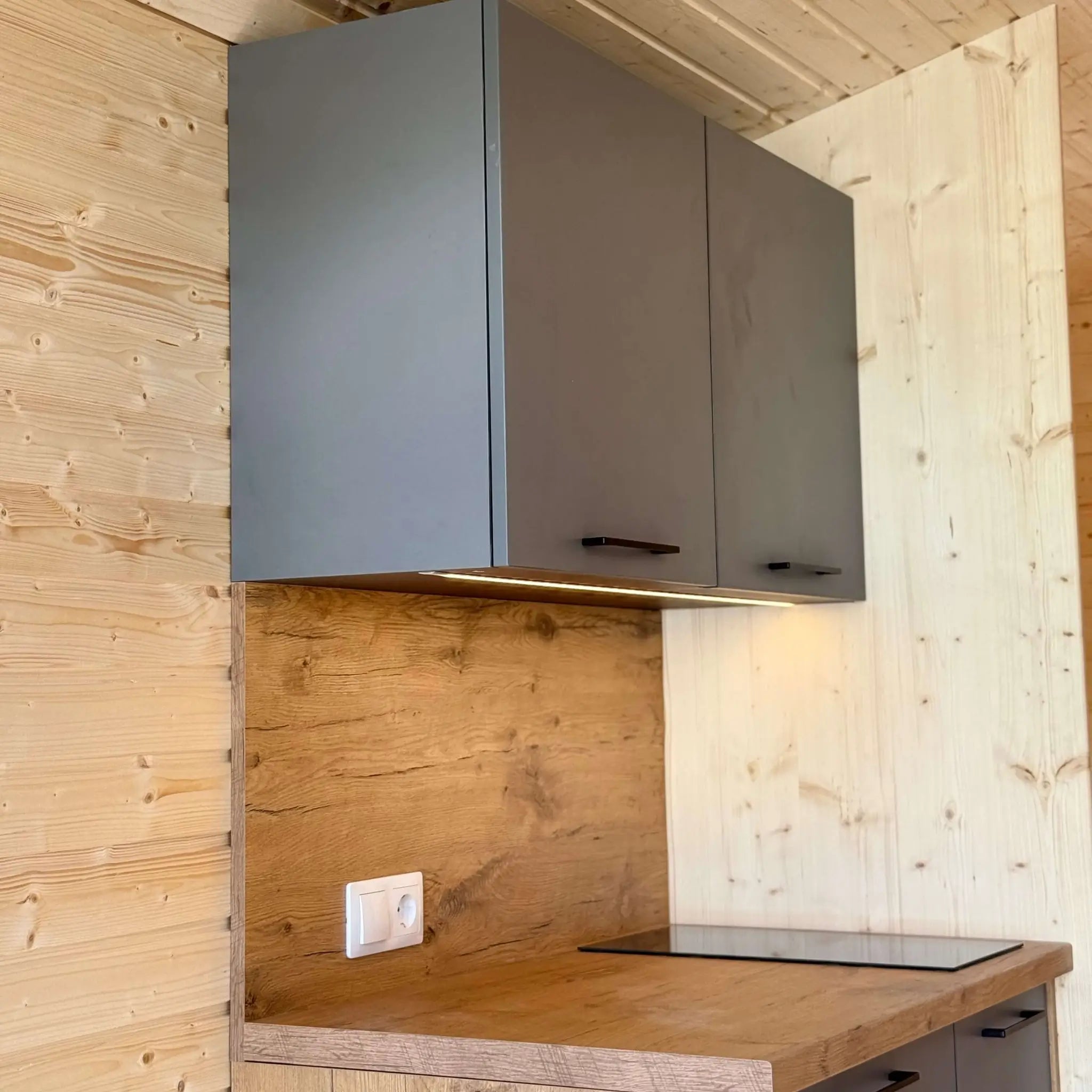 Kitchenette with wall-mounted cabinets and LED under-cabinet lighting inside The Ridgefall Pod 2 person glamping pod.