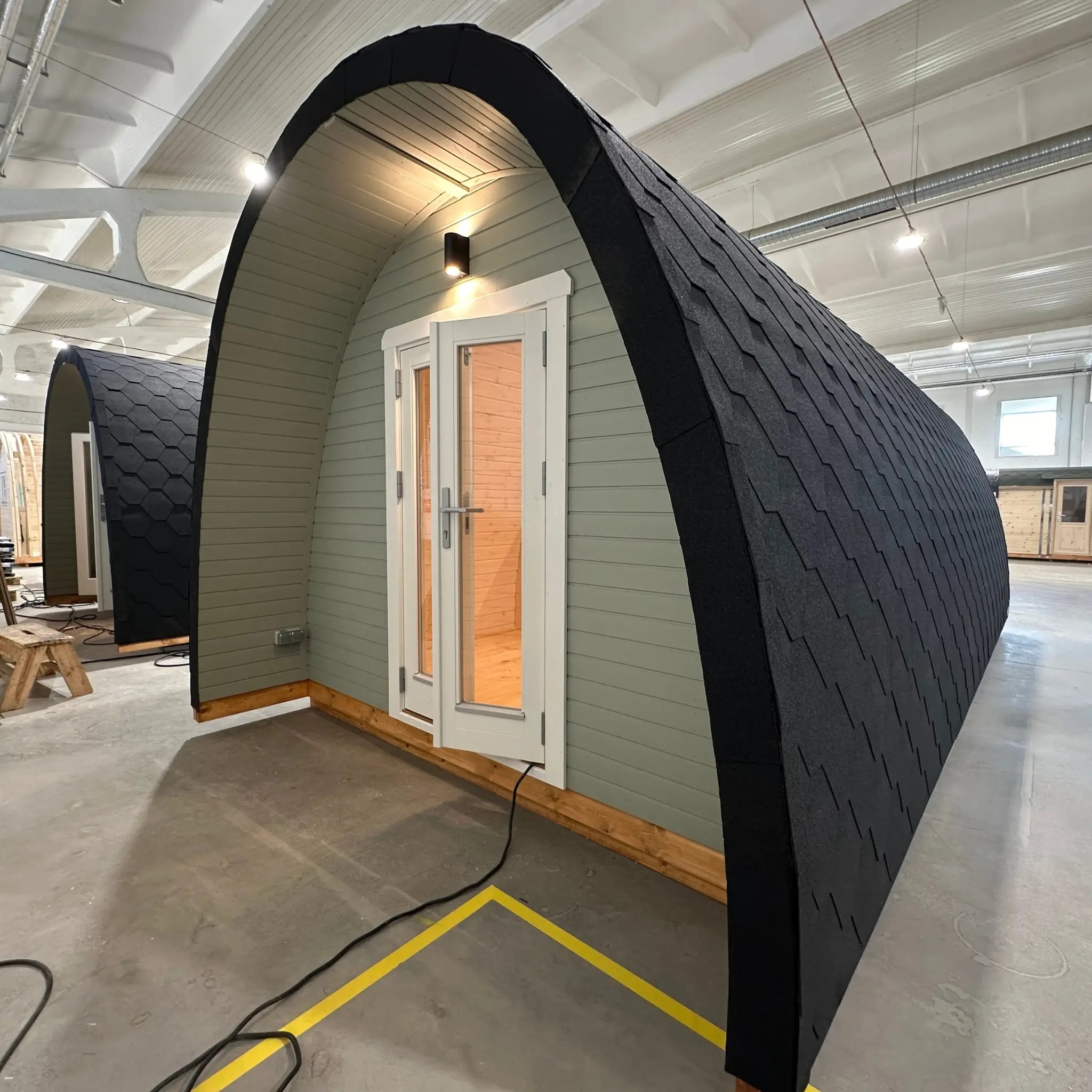 Front angled exterior view of The Twilight Pod showing insulated curved structure, timber entrance, and premium glamping pod design