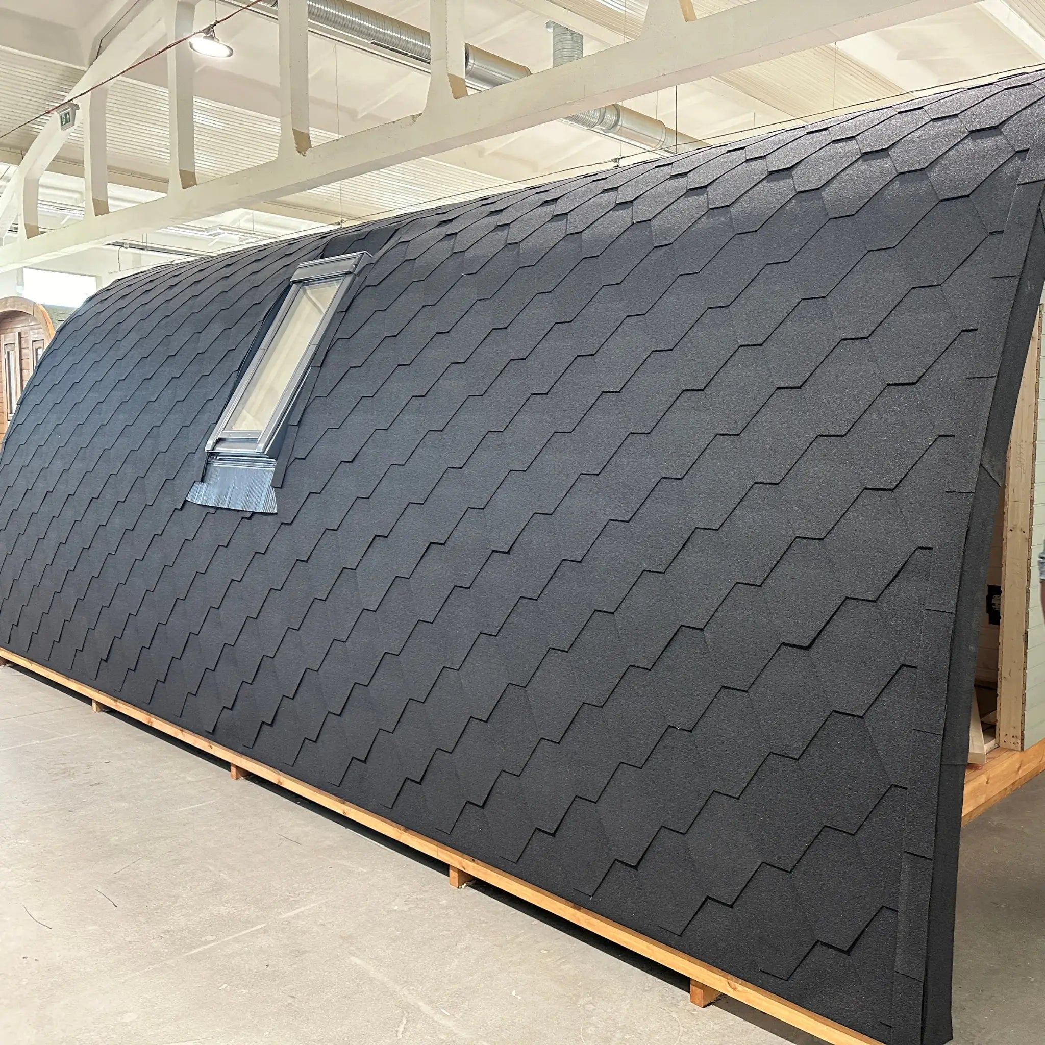 Side exterior view of The Twilight Pod luxury 2 person glamping pod featuring curved roof design and integrated VELUX roof window