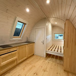 Angled interior view of The Twilight Pod showing kitchen counter, timber walls, and open-plan living space