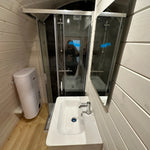 Bathroom layout inside the Twilight Pod with shower enclosure, wall-mounted sink, toilet, and natural wood flooring