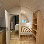 Interior view of the Twilight Pod showing bathroom entrance door and raised sleeping area with timber bed frame