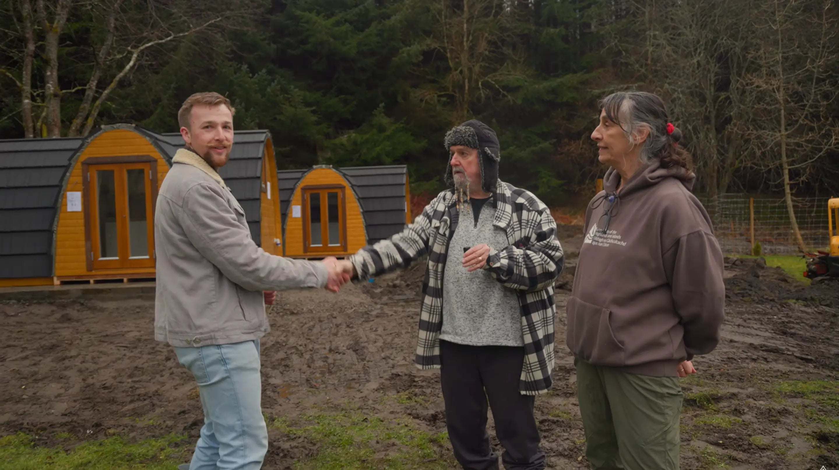 Taylor Glass shaking hands with Nigel Andrews while Margaret Andrews looks on at Doune House Pods following the successful delivery and installation of two Hobbit Pods in Scotland.
