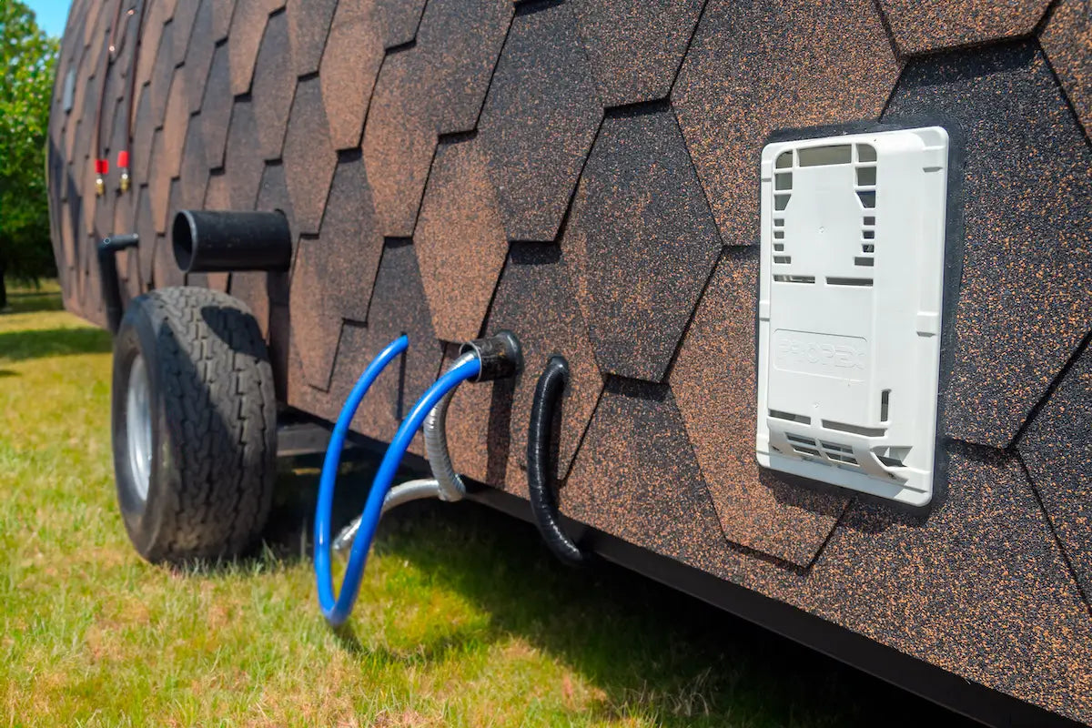 Close-up of an off-grid wooden pod with water and electrical connections, showcasing sustainable living features.