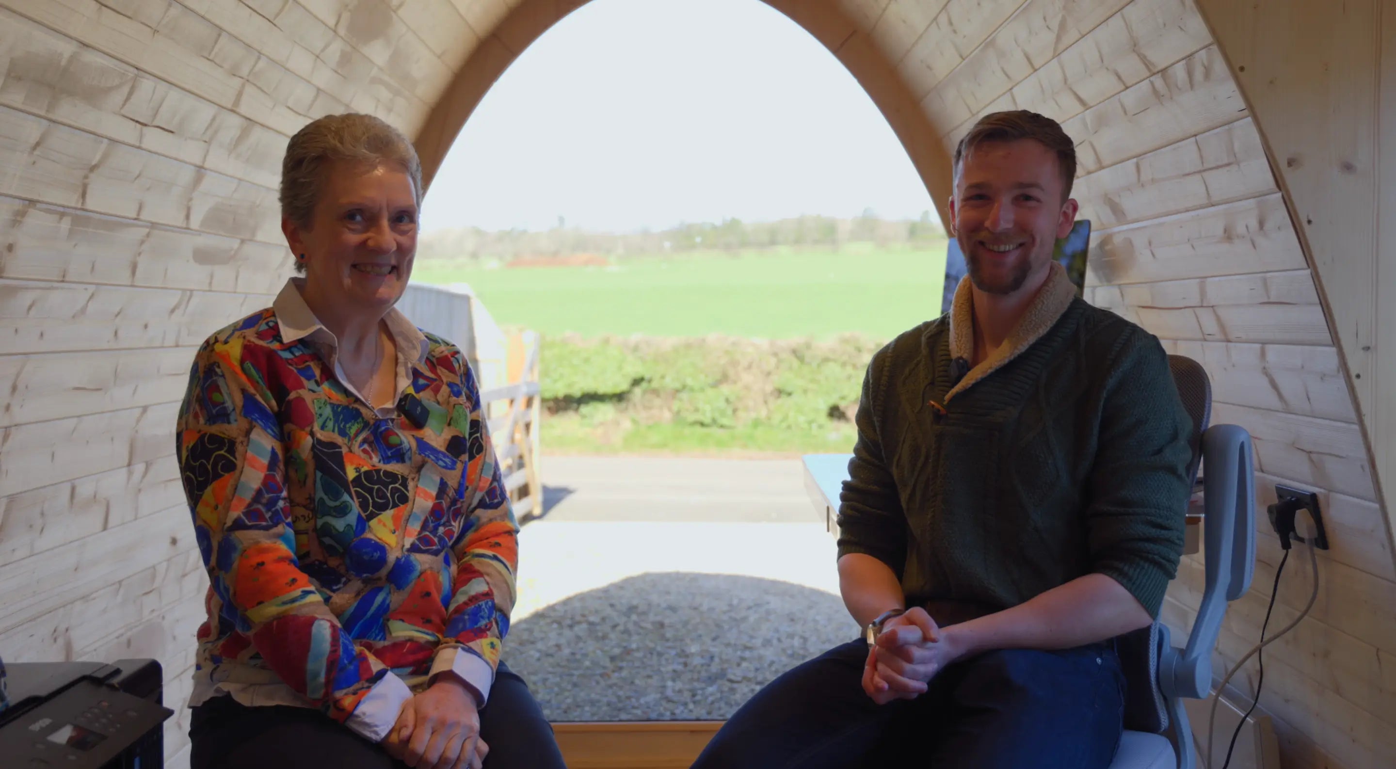 Aileen, a real GlampLaunch customer, providing a testimonial inside her completed bespoke garden office pod alongside founder Taylor Glass. The image highlights the personal relationships, customer satisfaction, and tailored approach behind every custom garden office project delivered by GlampLaunch.