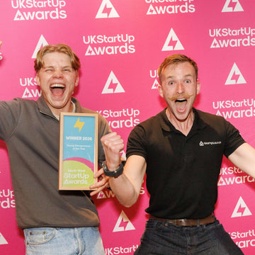 Two entrepreneurs celebrating at the UK StartUp Awards while holding a Young Entrepreneur of the Year finalist award.